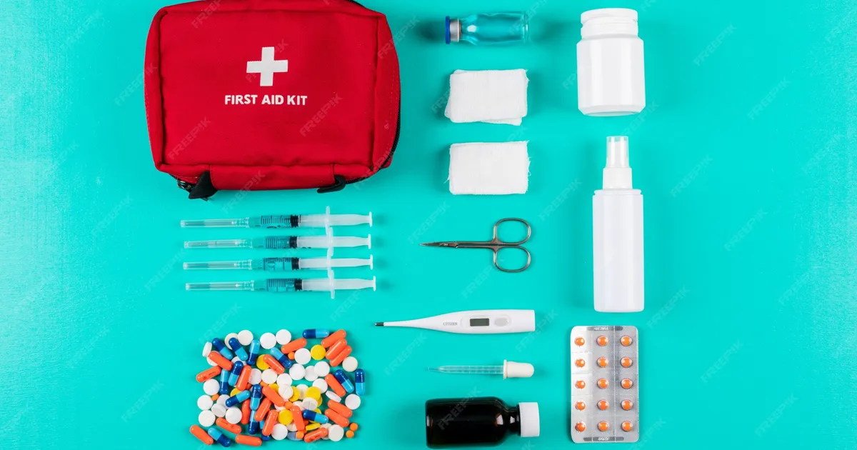 Material de un kit de emergencia escolar para niños organizado sobre una mesa: mini botiquín, linterna, tarjeta de contactos y agua