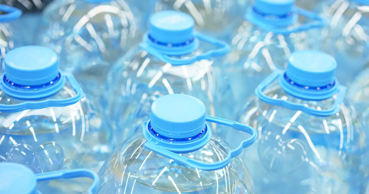 Bidones de agua azules apilados en trastero junto a garrafas de 8 litros preparadas para emergencias