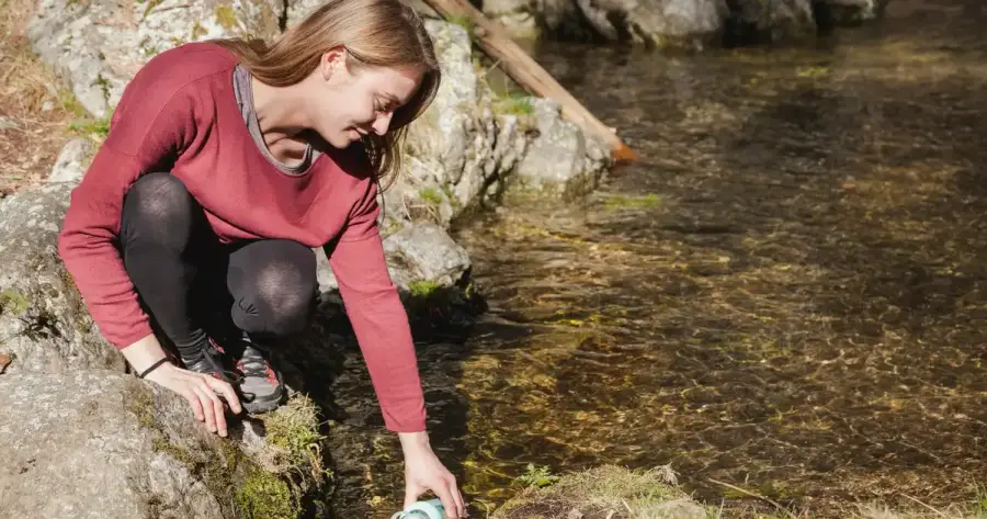 Pessoa a encher um cantil num rio de montanha, comparacao de metodos de purificacao de agua para emergencias