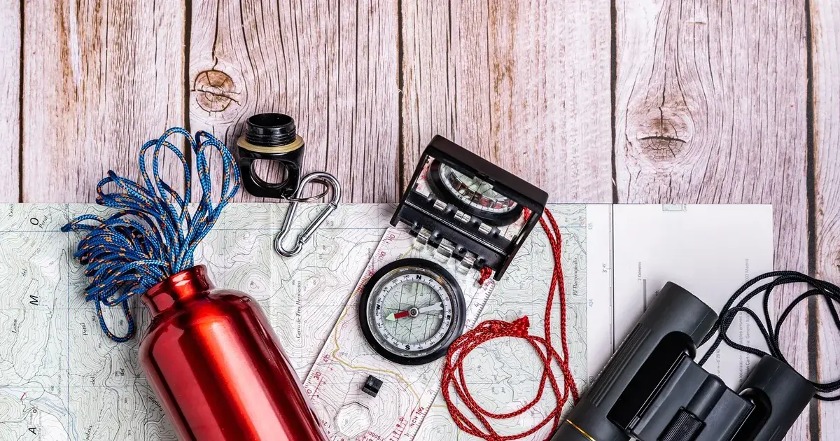 Equipo de supervivencia y material de emergencia organizado sobre mesa de madera para preparar un kit de 72 horas