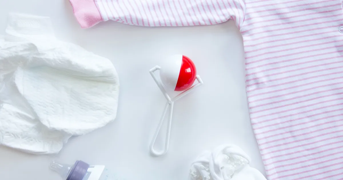 Flatlay de kit emergencia bebe con pañales, biberón con leche, pijama y accesorios sobre fondo blanco