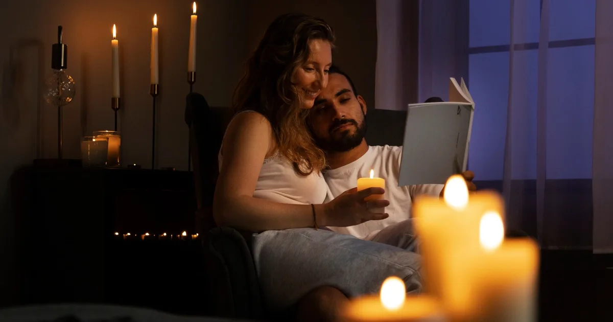 Casal lendo junto à luz de velas durante um apagão em casa — preparação apagão Brasil