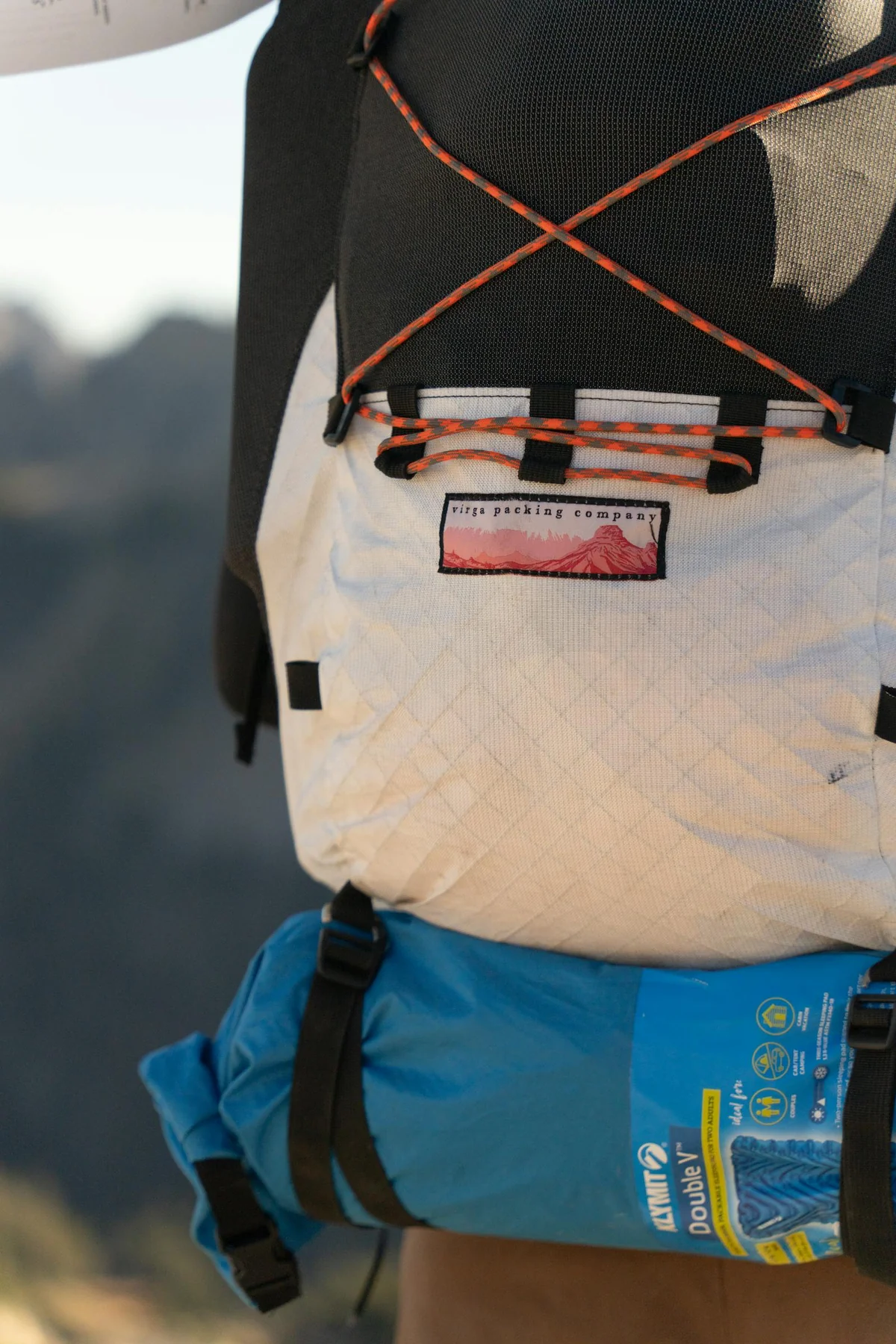 Survival backpack with gear laid out: flashlight, multi-tool, water, food, first-aid kit