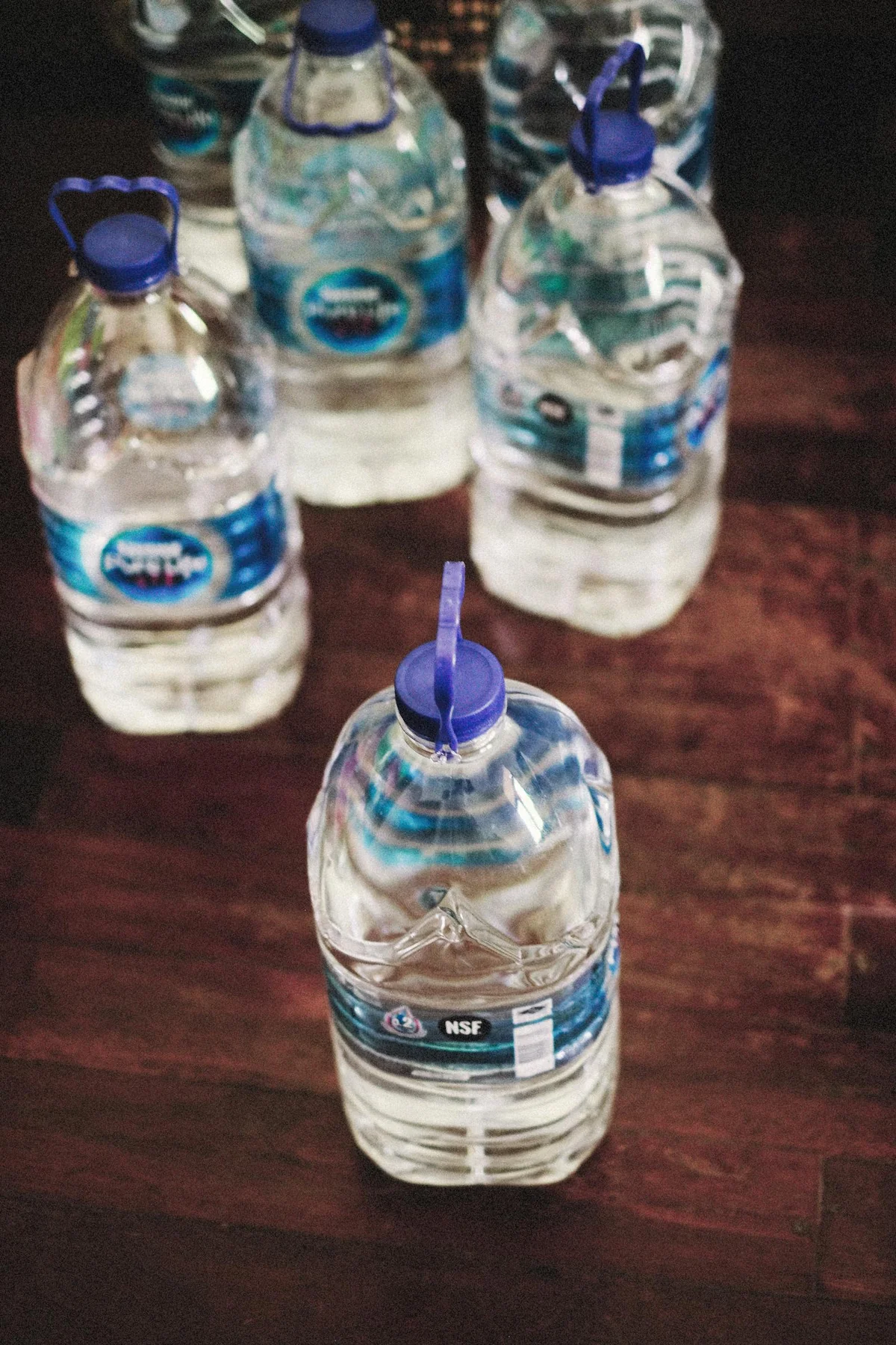 Botellas y garrafas de agua almacenadas en suelo de madera — reserva doméstica de agua para emergencias de 72 horas