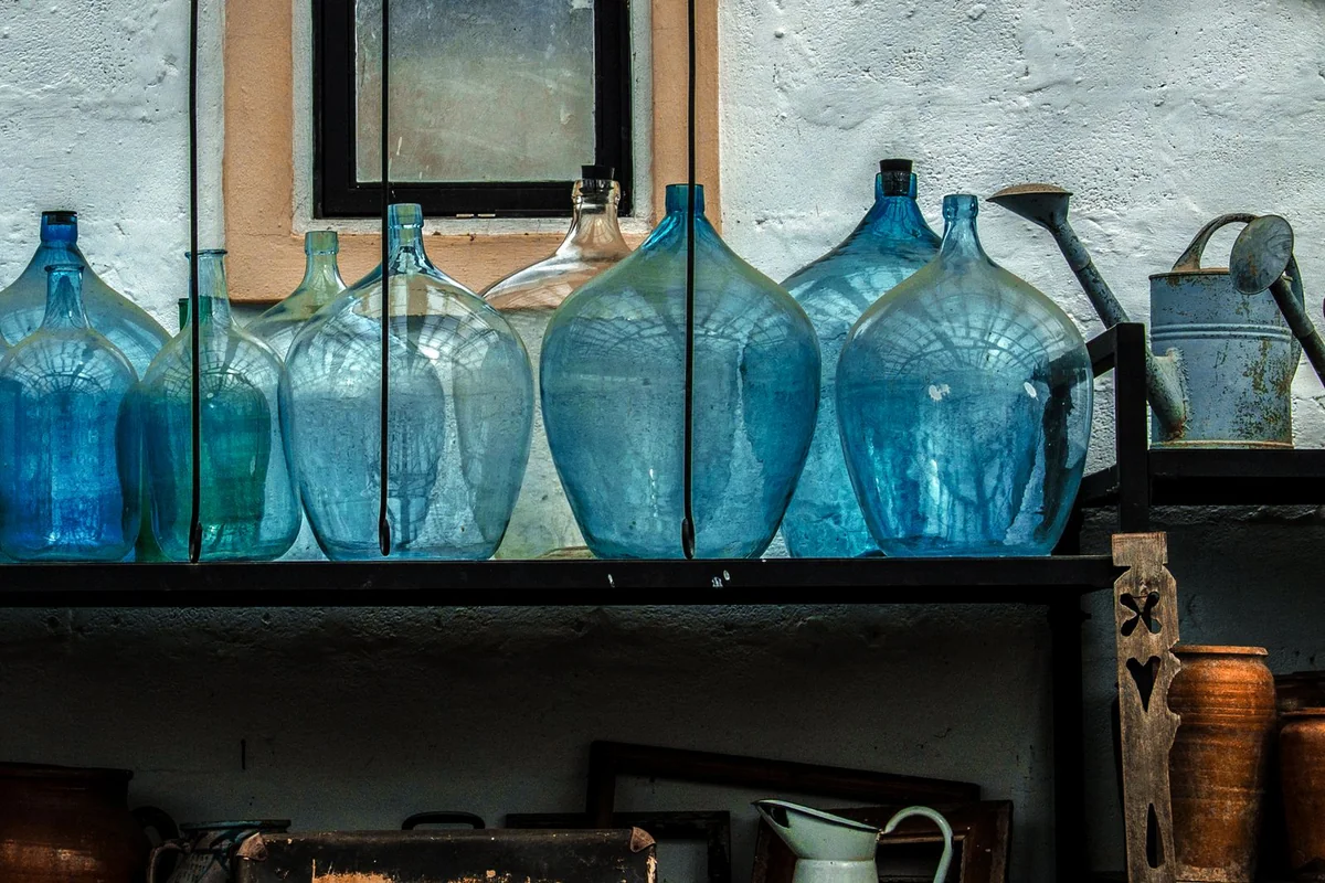 Botellas de cristal organizadas en estantería de despensa rural — almacenamiento ordenado de agua y reservas para emergencias domésticas