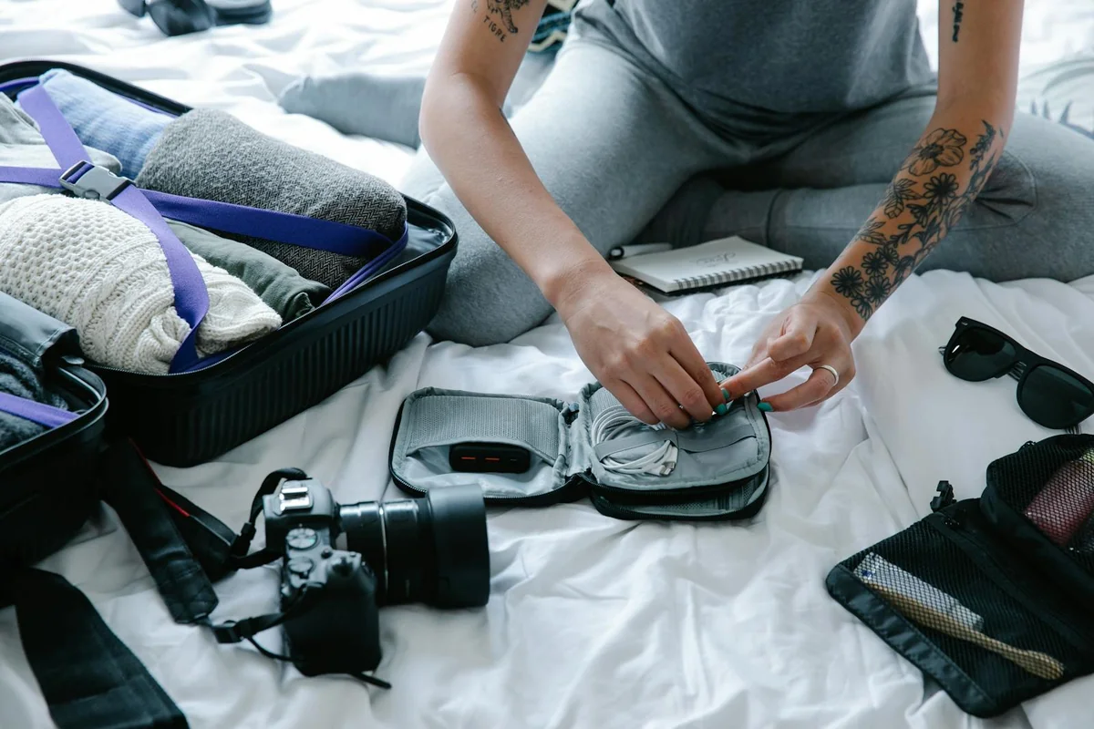 Manos preparando el contenido de una mochila de evacuación sobre la cama — montaje paso a paso de bolsa de 72 horas