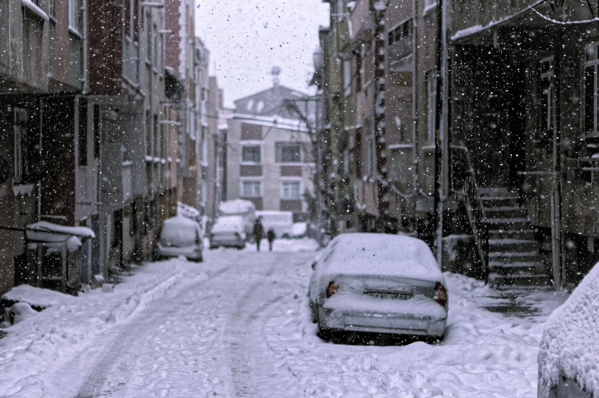 Calle nevada con coches enterrados bajo gruesa capa de nieve — escenario de gran nevada urbana tipo Filomena en Madrid