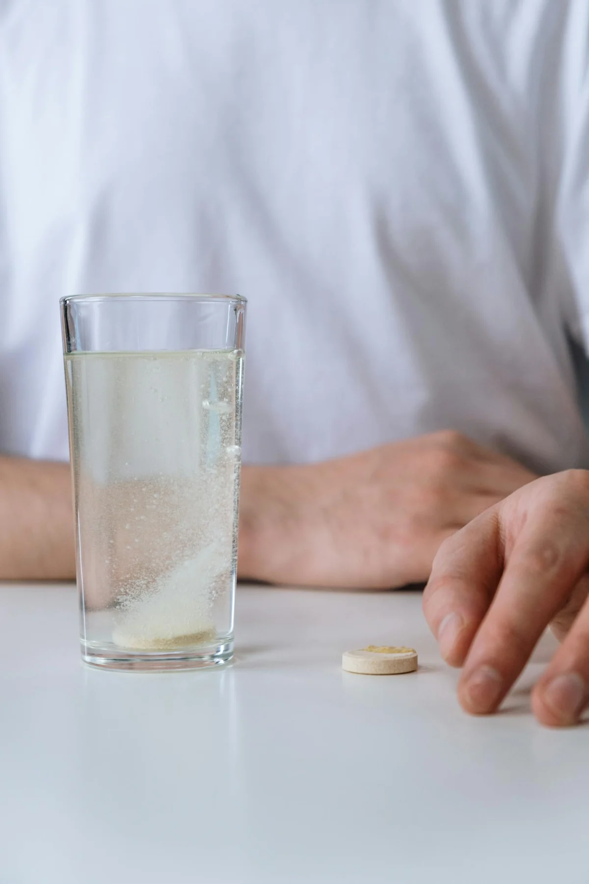 Pastilla disolviéndose en un vaso de agua transparente — potabilización química de agua de emergencia con tabletas
