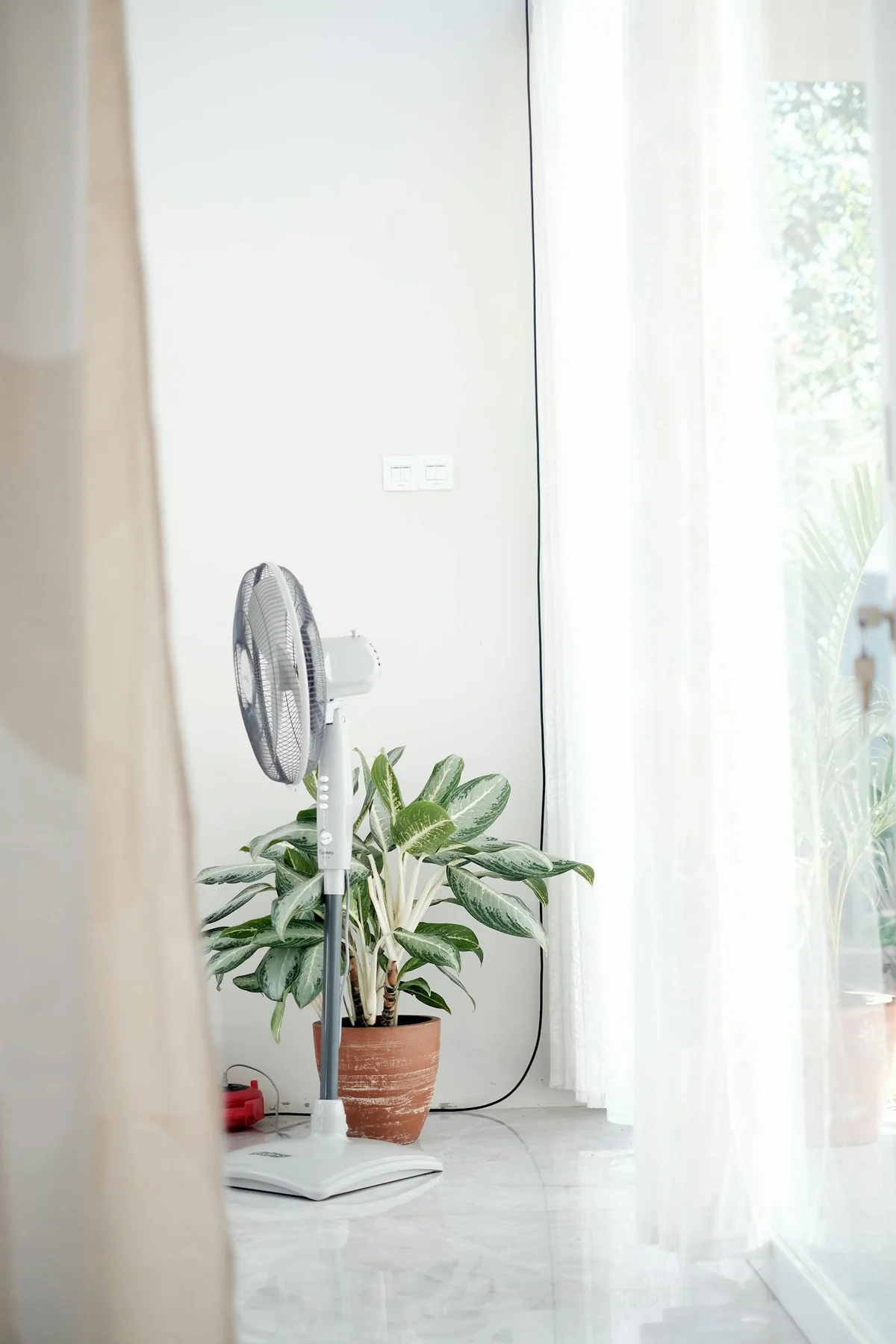 Ventilador de pie en interior doméstico minimalista — refrigeración pasiva durante ola de calor sin aire acondicionado