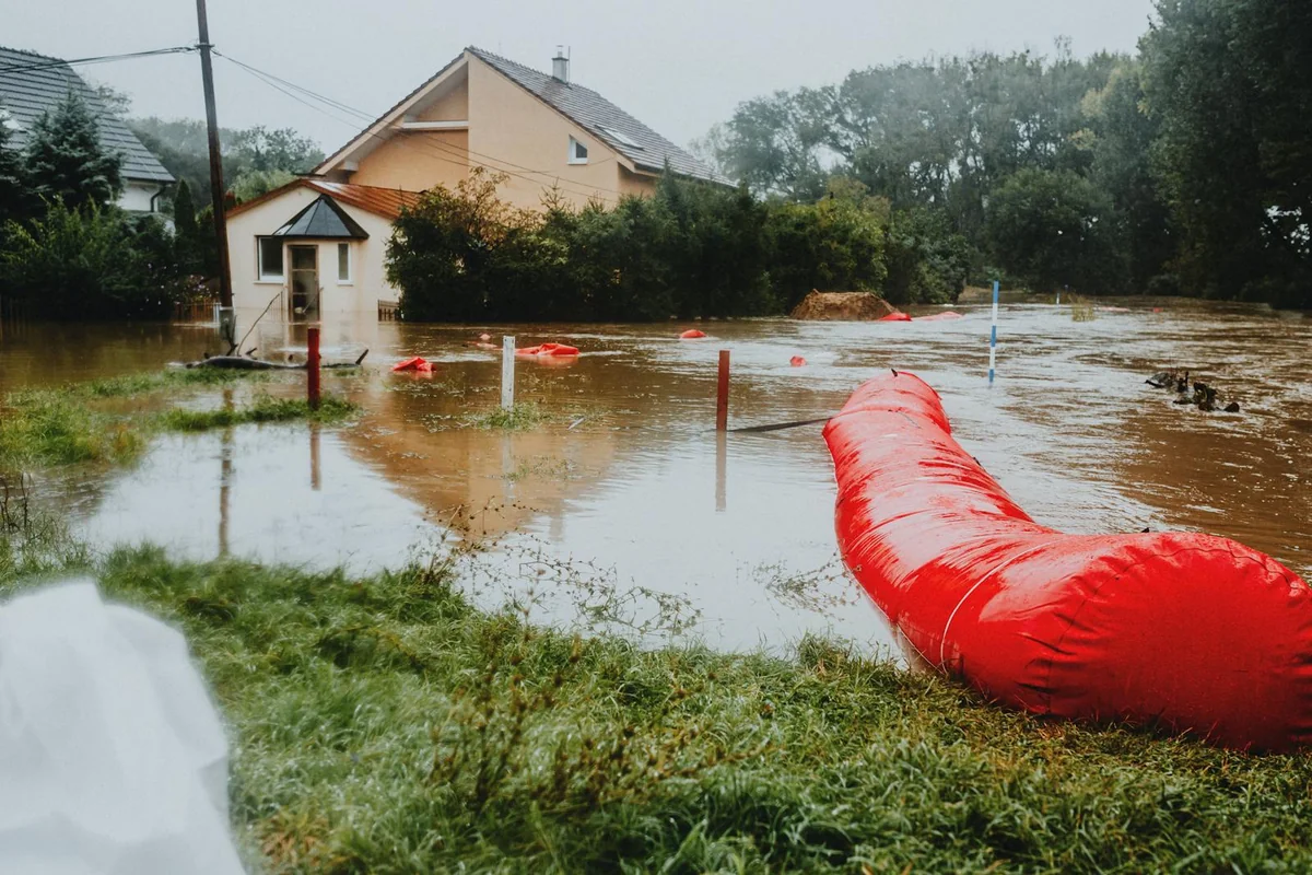 Barreras rojas contra inundación protegiendo una zona residencial — mitigación pasiva de daños por crecida en zonas inundables