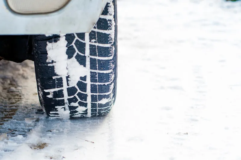 Coche circulando con cadenas en carretera cubierta de nieve en invierno
