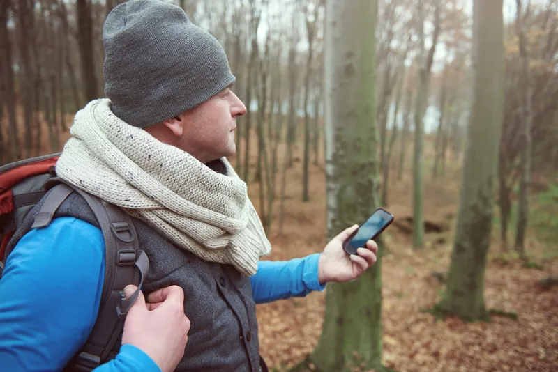 Excursionista buscando señal de comunicador GPS en zona de montaña sin cobertura