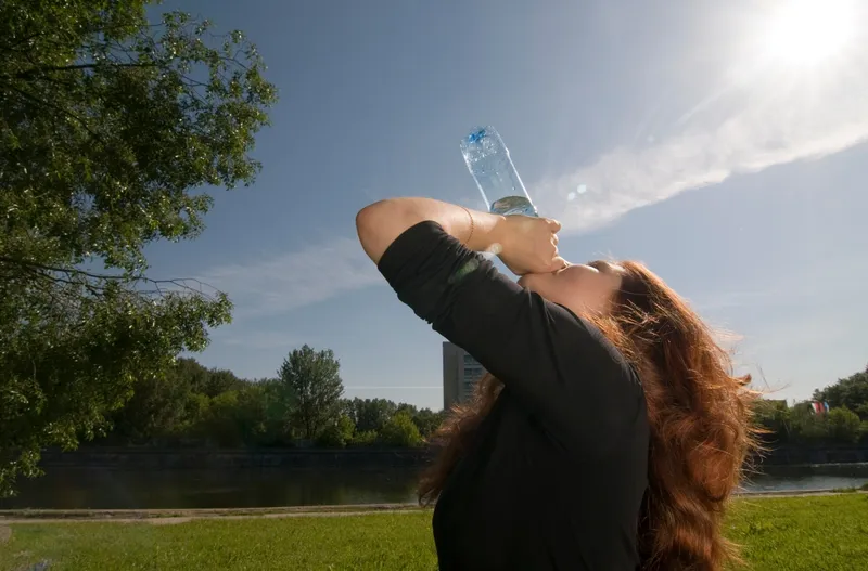 Pessoa a hidratar-se num dia de calor extremo com garrafa de água